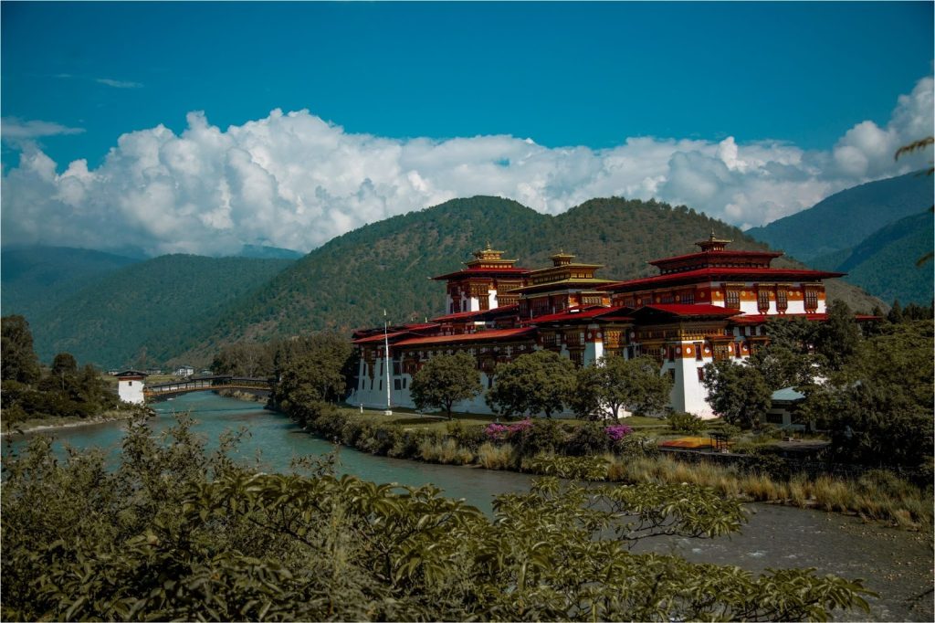  Punakha Dzong in Bhutan beside the river with forested mountains, highlighting the nation’s environmental conservation efforts and cultural heritage.