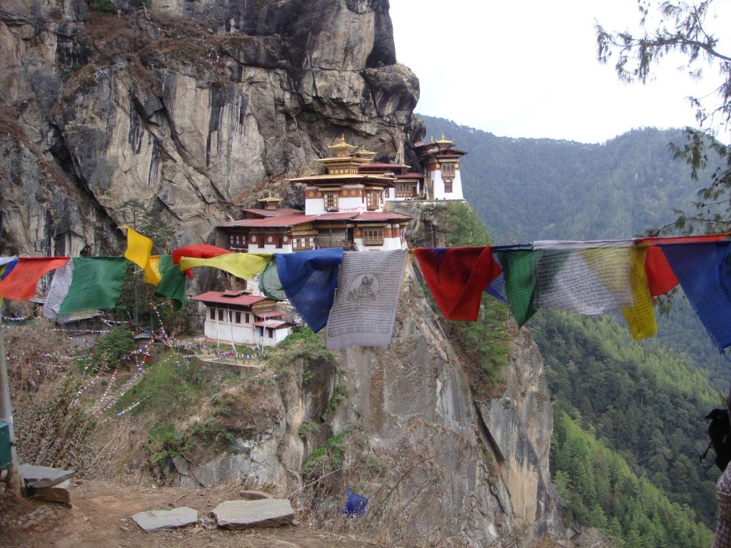 Tiger’s Nest Monastery in Bhutan perched on a cliffside, surrounded by lush green forests and mountains, reflecting Bhutan’s commitment to environmental conservation and cultural heritage.