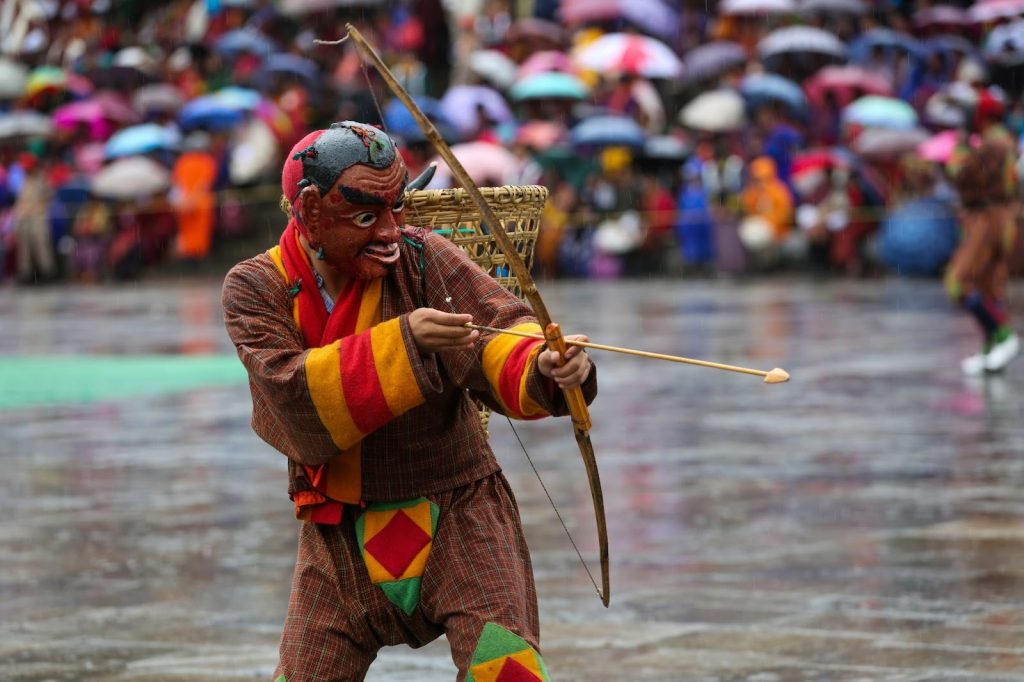  Bhutanese mask dancer in colourful traditional costume performing at a cultural festival, showcasing Bhutan’s heritage and Gross National Happiness values