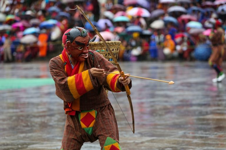 Bhutanese mask dancer in colourful traditional costume performing at a cultural festival, showcasing Bhutan’s heritage and Gross National Happiness values